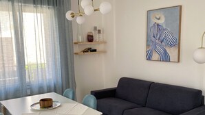 A modern living room with a dining table, chairs, a sofa, a painting, and a pendant light. - Villa Luigia Garda. "Azure" (Peschiera del Garda)