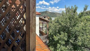 A wooden balcony with a view of a mountain and lush greenery. - River Front Mtskheta (Mtskheta)