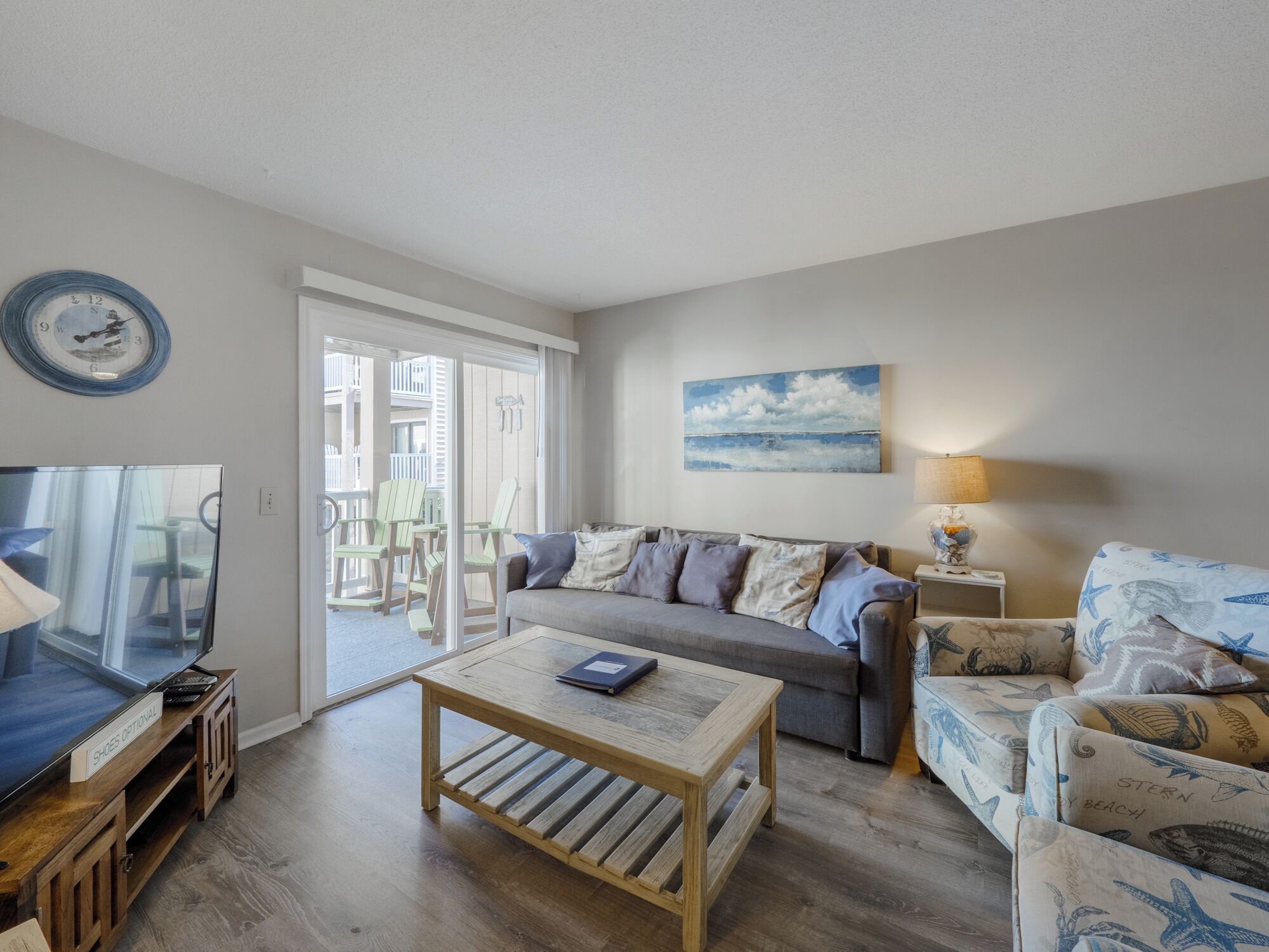 A living room with a sofa, a coffee table, a television, and a painting on the wall.