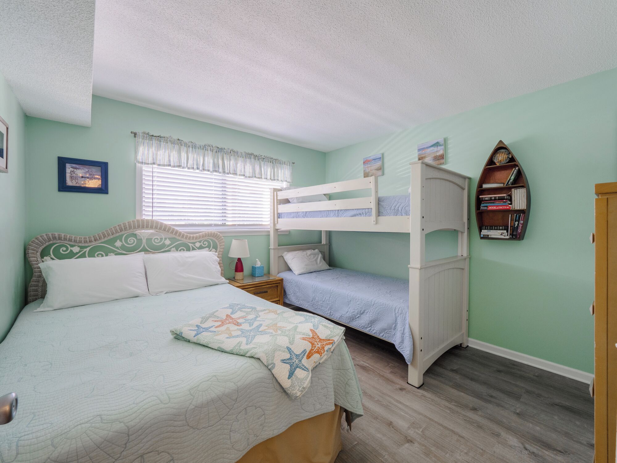 A bedroom with a bunk bed, a single bed, and a nightstand with a lamp.