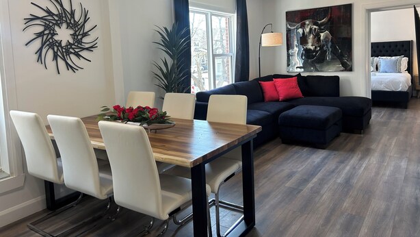Un salon moderne comprenant un coin repas, un canapé, un lit et une grande fenêtre.