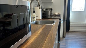 Une cuisine moderne avec un plan de travail en bois, des appareils électroménagers en acier inoxydable et une grande fenêtre.