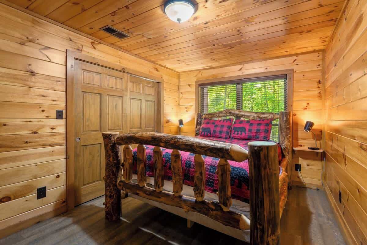 A wooden cabin room with a bed, a window, and a door.