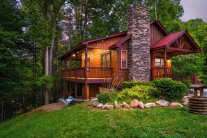 Eine zweistöckige Blockhütte mit Steinofen, Holzfassade und einer Veranda mit Lichterketten.