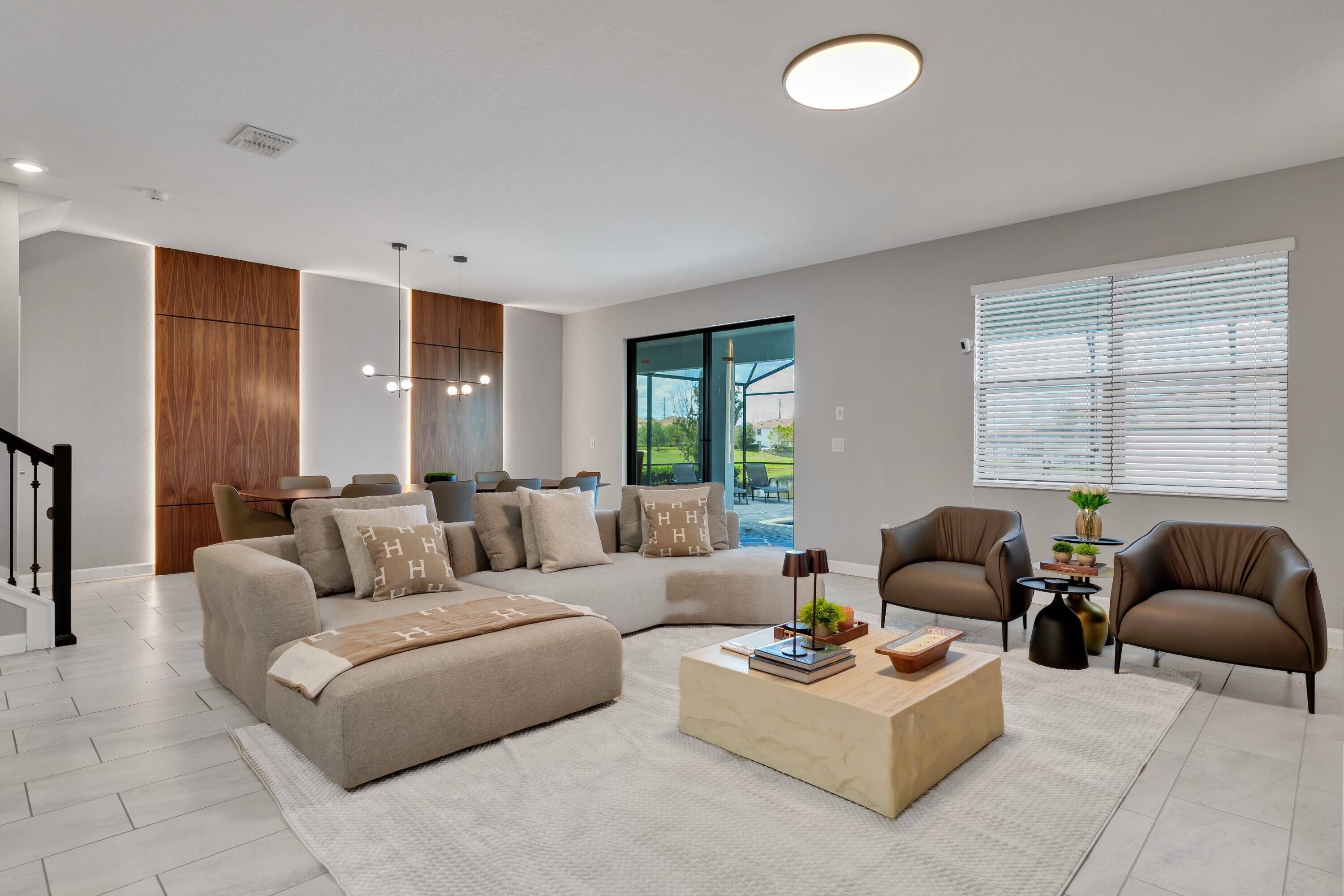 A modern living room with a sectional sofa, a coffee table, and two armchairs.