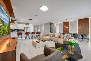 Un salon moderne avec un canapé d’angle, une table basse et un coin repas avec des chaises.