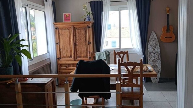 En matplats med ett bord, stolar, ett skåp och en surfbräda.