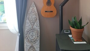 Ett rum med en gitarr, en surfbräda och en krukväxt.