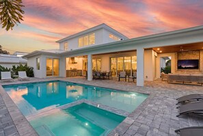 Ein modernes Haus mit Swimmingpool, Sitzgelegenheit im Freien und einem großen Fenster mit Blick auf den Pool.