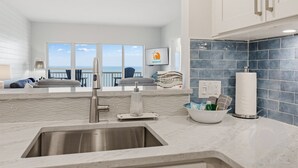 Una cocina moderna con un ventanal grande, vista al océano y un salpicadero de azulejos azules.