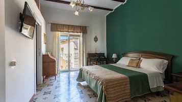Un dormitorio con cama, escritorio, silla, cómoda, espejo y vista al exterior.
