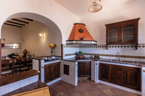 A kitchen with wooden cabinets, a stove, and a tiled backsplash. - La Palommella (Massa Lubrense)