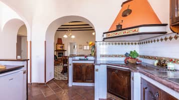 Una cocina con una isla central, armarios de madera, salpicadero de azulejos y un arco que lleva a otra habitación.