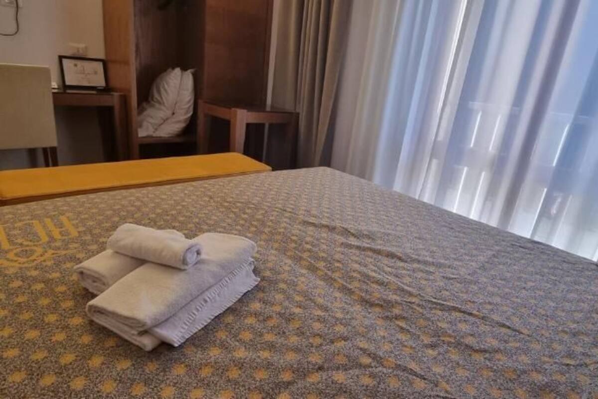 Una camera d'albergo con un letto, una scrivania, una sedia e una finestra con tende.