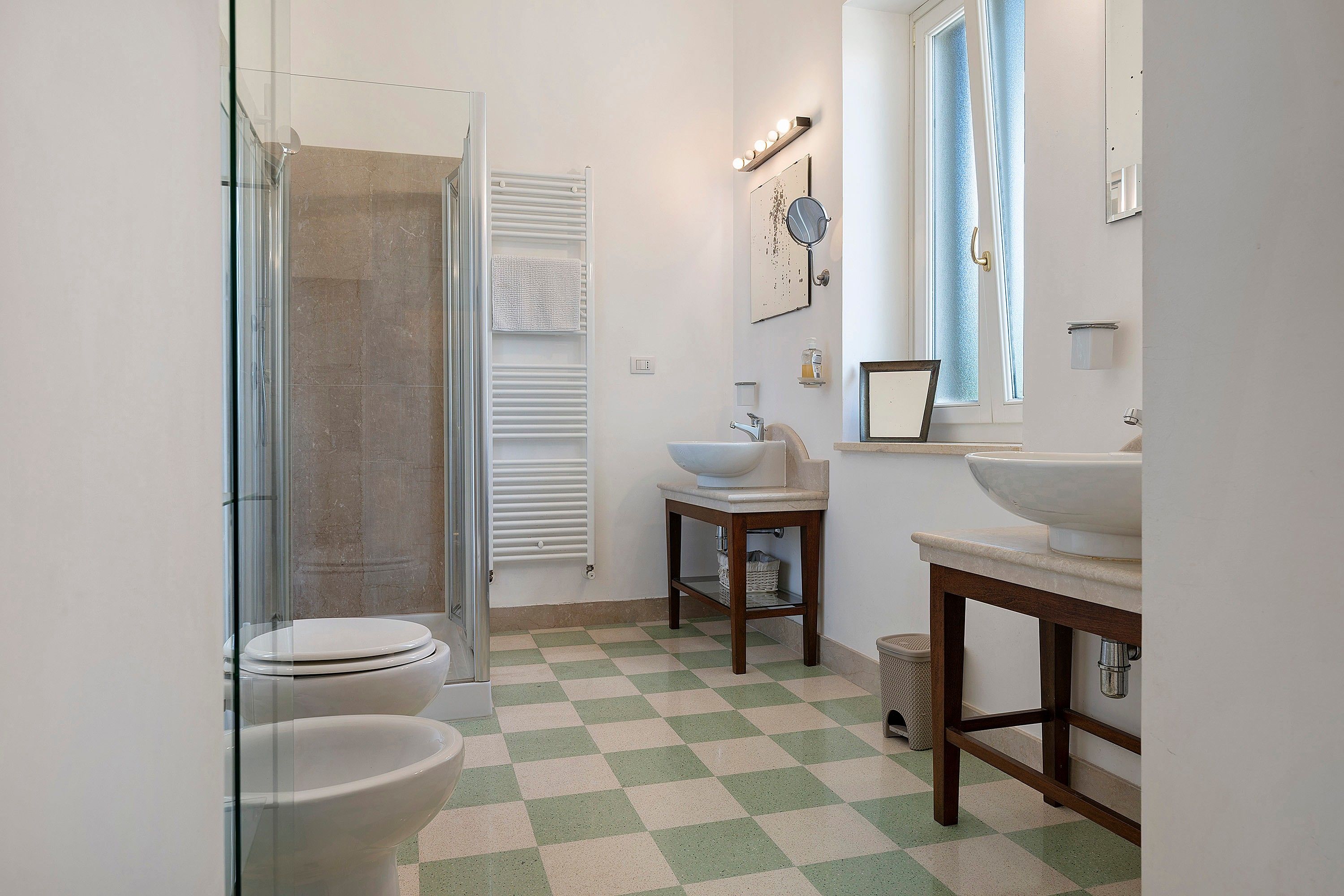 A bathroom with a glass shower enclosure, a toilet, a sink, and a mirror.