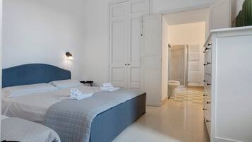 A hotel room with a bed, a bedside table, a wardrobe, and a shower area.