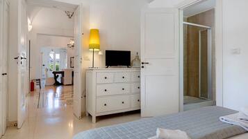 Een hotelkamer met een bed, een dressoir, een televisie en een badkamers deur.