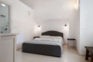 Une chambre à coucher comprenant un lit, des tables de chevet, un miroir et des lampes fixées au mur.