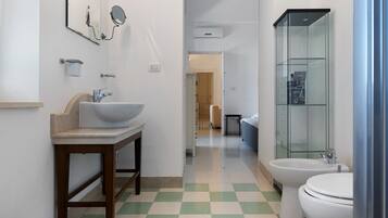 A bathroom with a sink, mirror, toilet, and shower.