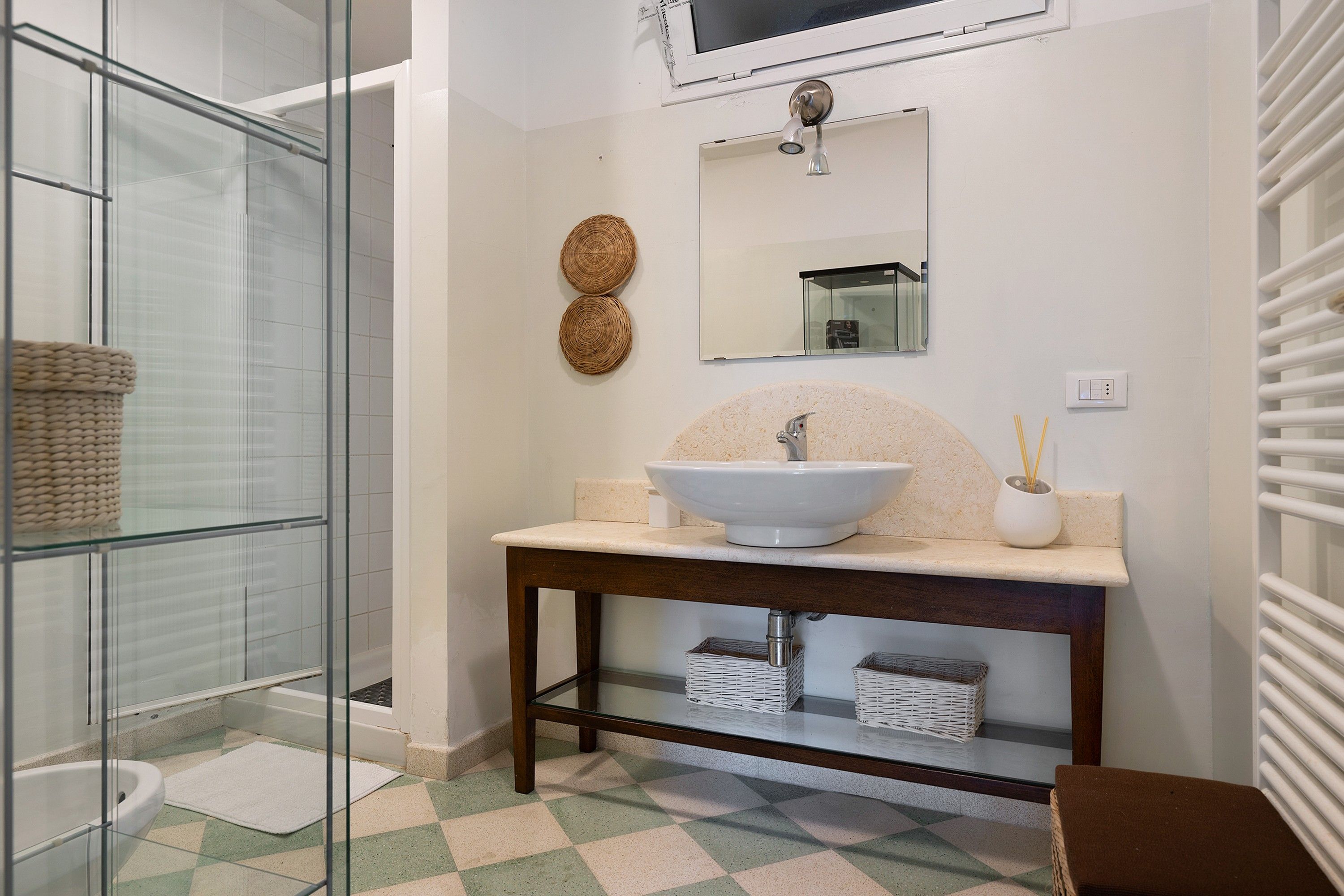 Une salle de bain avec une douche à parois de verre, un lavabo à cuve ronde et un miroir au-dessus.