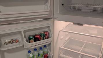 Un refrigerador obert amb prestatges que contenen begudes i aperitius.
