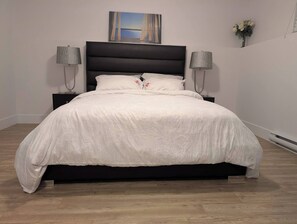 A bed with a white bedspread, a dark headboard, and two bedside lamps.
