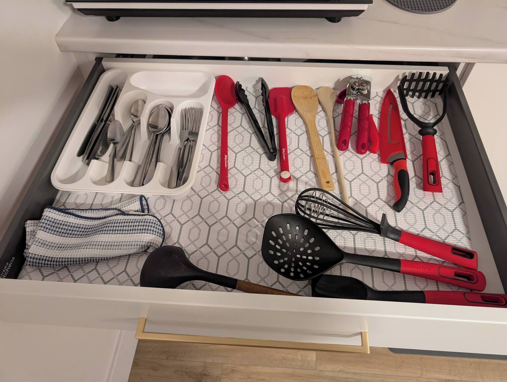 Un tiroir de cuisine contenant des ustensiles, notamment des spatules, des fouets et une râpe.