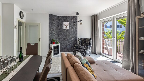 A modern living room with a sofa, dining table, and a chair. There is a window with a view of the outside. - Cozy Apartment in Willingen, Usseln – Lovingly Furnished for a Relaxing Atmosphere (Willingen (Upland))