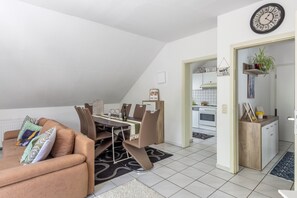 A modern kitchen with white cabinets, a wooden countertop, and a hanging clock. - Cozy Apartment in Willingen, Usseln – Lovingly Furnished for a Relaxing Atmosphere (Willingen (Upland))
