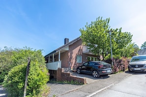 A two-story brick house with a car parked in the driveway and a street lamp nearby. - Cozy Apartment in Willingen, Usseln – Lovingly Furnished for a Relaxing Atmosphere (Willingen (Upland))