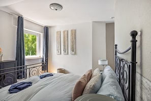 Een slaapkamer met een bed, gordijnen, een lamp en wanddecoratie.