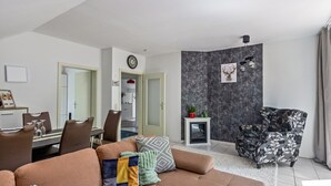 A modern living room with a sofa, a dining area with chairs, a fireplace, and a decorative chair. - Cozy Apartment in Willingen, Usseln – Lovingly Furnished for a Relaxing Atmosphere (Willingen (Upland))