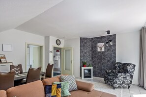 Una sala moderna con un sofá, un comedor con sillas, una chimenea y una butaca decorativa.