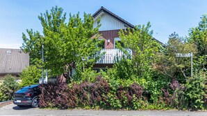A residential building with a brick facade, white trim, and a visible garage door. - Cozy Apartment in Willingen, Usseln – Lovingly Furnished for a Relaxing Atmosphere (Willingen (Upland))