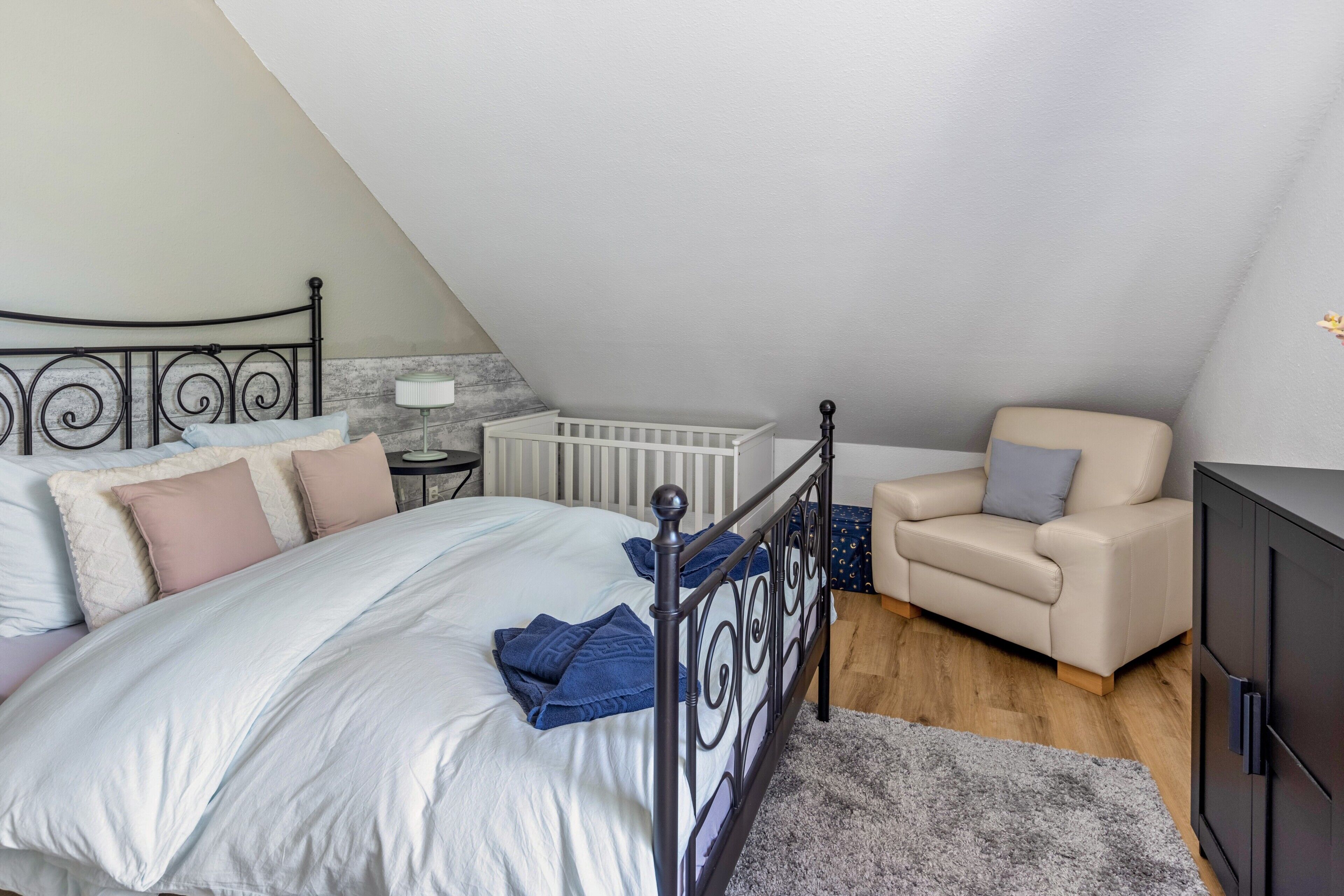 Una camera da letto con un letto, una sedia, un armadio e una culla.