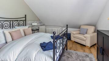 Una camera da letto con un letto, una sedia, un armadio e una culla.