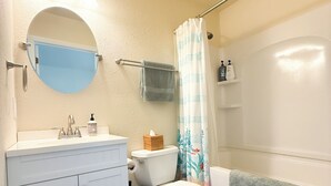 A bathroom with a toilet, sink, mirror, and shower. - Tiny home in lovely Rockport TX-Frigate House #2 (Rockport)