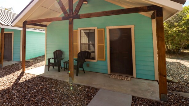 A building with a covered porch, two chairs, a door, and a window. - Tiny home in lovely Rockport TX-Frigate House #2 (Rockport)