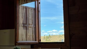 A wooden interior with a dining table and chairs, a window with curtains, and a refrigerator. - Cabin Varde | 2-bedroom cabin in charming Žabljak (Žabljak)
