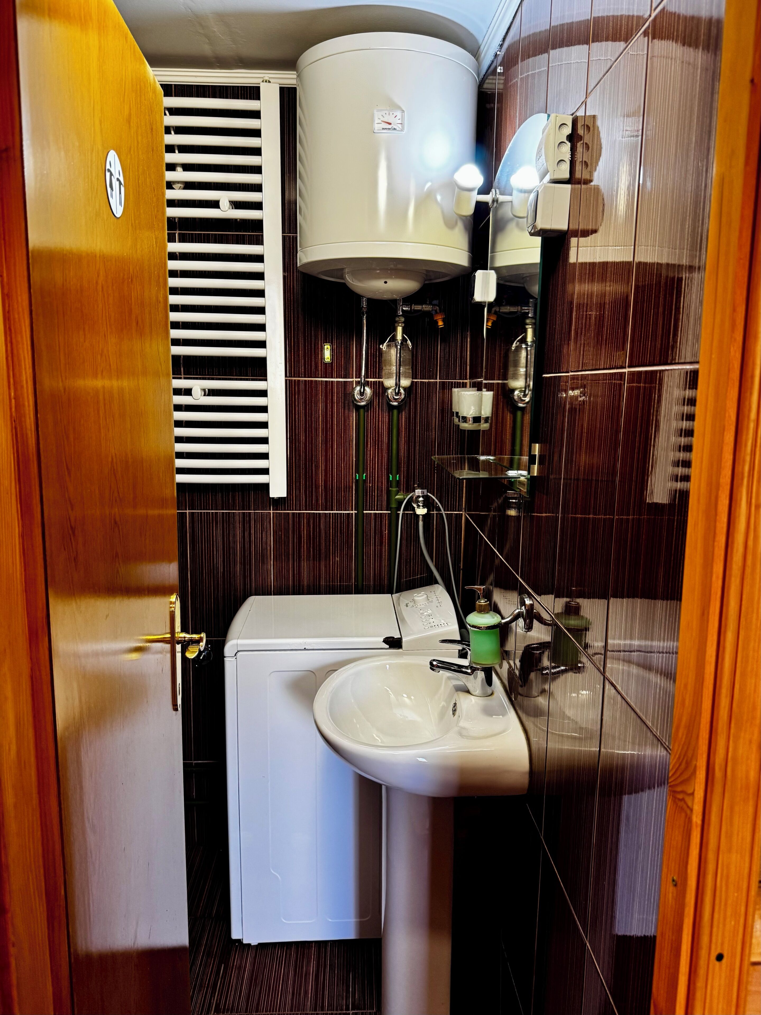 Et lille badeværelse med toilet, vask og en lille vaskemaskine.