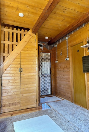 A wooden interior with a staircase, a door with a metal gate, and a wall-mounted light fixture. - Cabin Varde | 2-bedroom cabin in charming Žabljak (Žabljak)