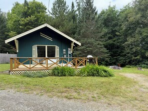 A small cabin with a porch and a deck, surrounded by dense forest. - Cozy 1-bedroom cabin in quaint Coplin, with AC and gas fireplace. (Coplin plantation)