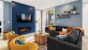 A modern living room with a fireplace, a flat-screen TV, and a sofa. - Obermiller House ~ Spectacular Sunset~Modern~Rooftop~AC+Games+Parking (Seattle)