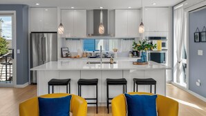 A modern kitchen with a central island, stainless steel appliances, and pendant lighting. - Obermiller House ~ Spectacular Sunset~Modern~Rooftop~AC+Games+Parking (Seattle)
