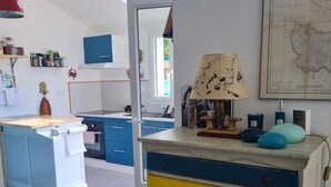Une cuisine avec une lucarne, un meuble en bois doté de tiroirs, une carte accrochée au mur et un téléviseur.