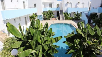 Una piscina al aire libre de temporada, sombrillas, tumbonas