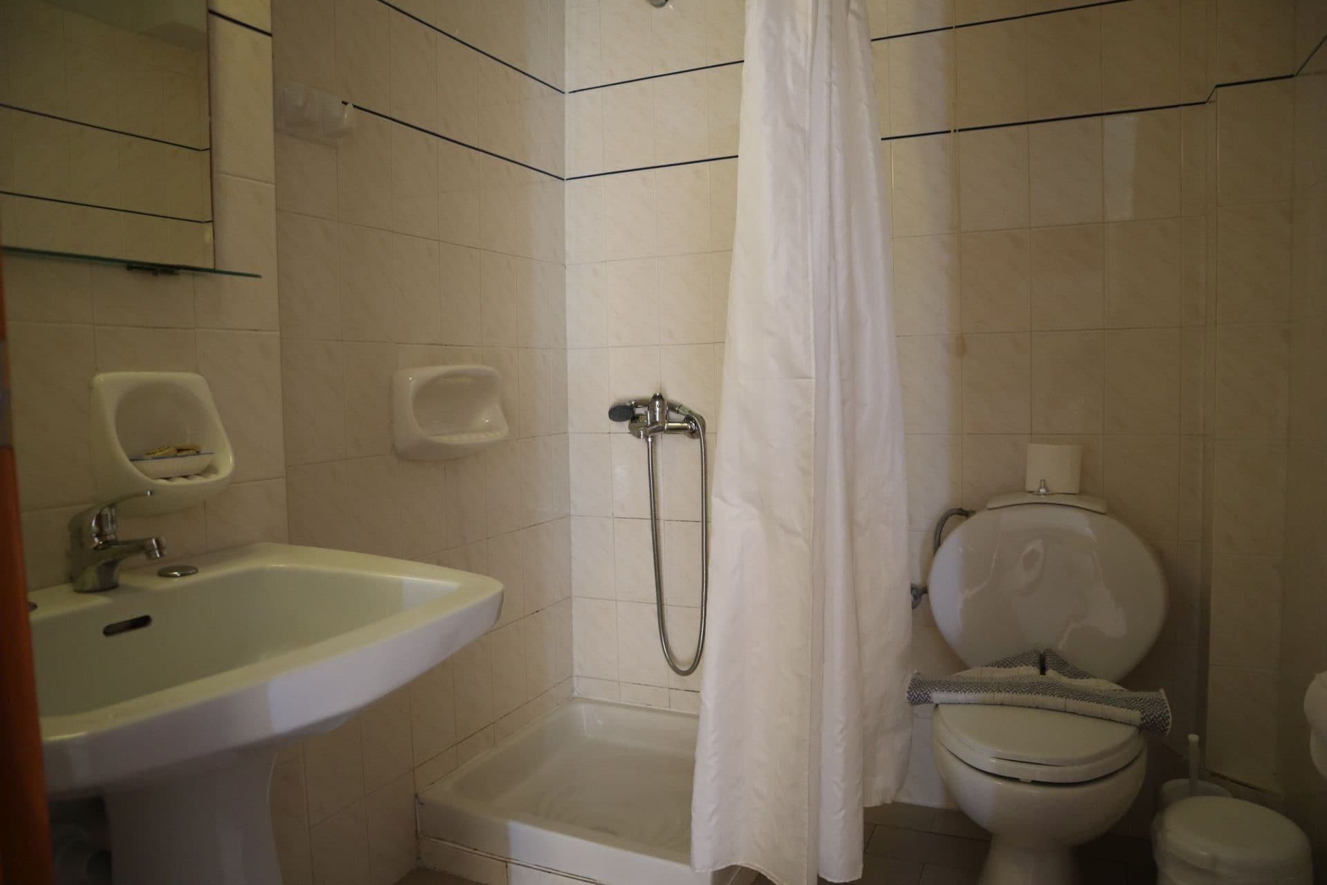 A bathroom with a sink, toilet, shower, and a curtain.