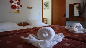 Ein Hotelzimmer mit zwei Betten, einer Holztür, einem Spiegel und einer Wanddekoration.