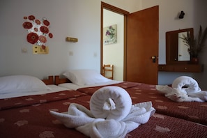 Hotellihuone, jossa on kaksi sänkyä, puuovi, peili ja seinäkoriste.