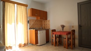 Eine kleine Küche mit Holzausstattung, einem Kühlschrank, einem Spülbecken und einem Esstisch mit Stühlen.